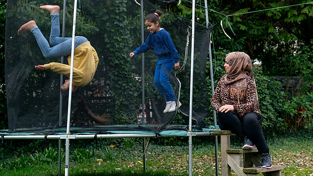 Kinderen op een trampoline en een vrouw met hoofddoek